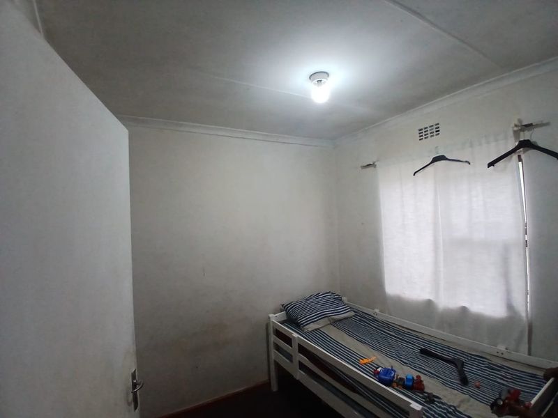 A compact bedroom featuring plain walls, a ventilation grille, and coving, requiring cosmetic updates to improve its overall condition and appeal.