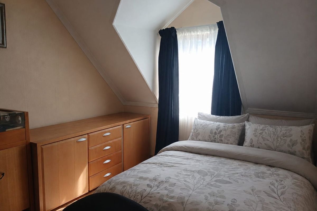 A cozy bedroom featuring a sloped ceiling, a dormer window, and built-in wooden cabinetry providing ample storage space.