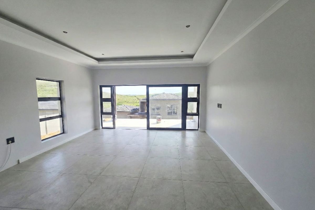 A bright, spacious, and empty living area featuring modern tiled floors, recessed ceiling details, and large aluminium sliding doors leading to an outdoor space.