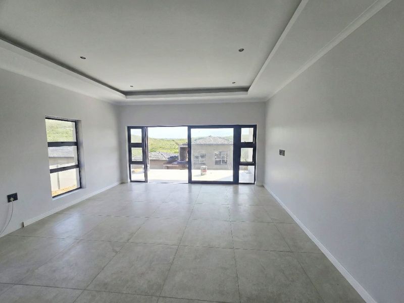 A bright, spacious, and empty living area featuring modern tiled floors, recessed ceiling details, and large aluminium sliding doors leading to an outdoor space.