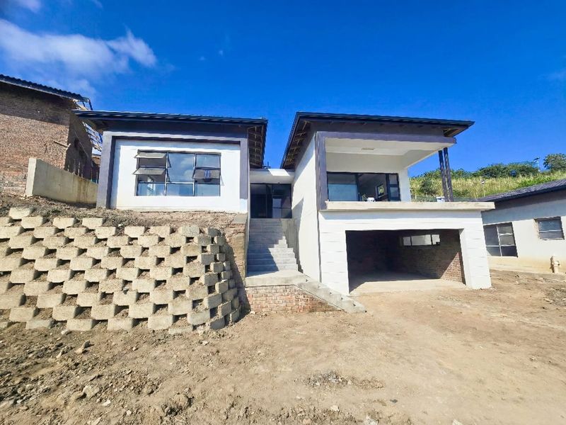 Front elevation of a modern two-story house under construction, featuring a concrete staircase, integrated garage, and balcony with unfinished surrounding landscaping.