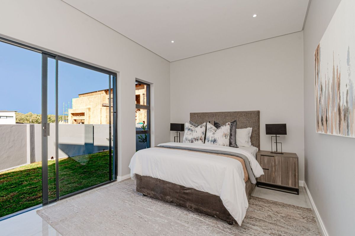 Modern bedroom featuring neutral tones, recessed lighting, and large sliding glass doors providing direct access to the garden area.