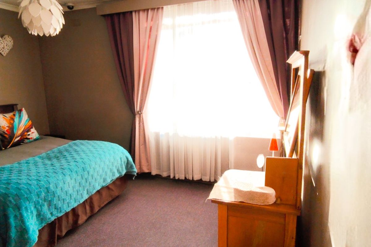 A bedroom featuring carpeted flooring and coved ceiling details, illuminated by natural light from a large window.