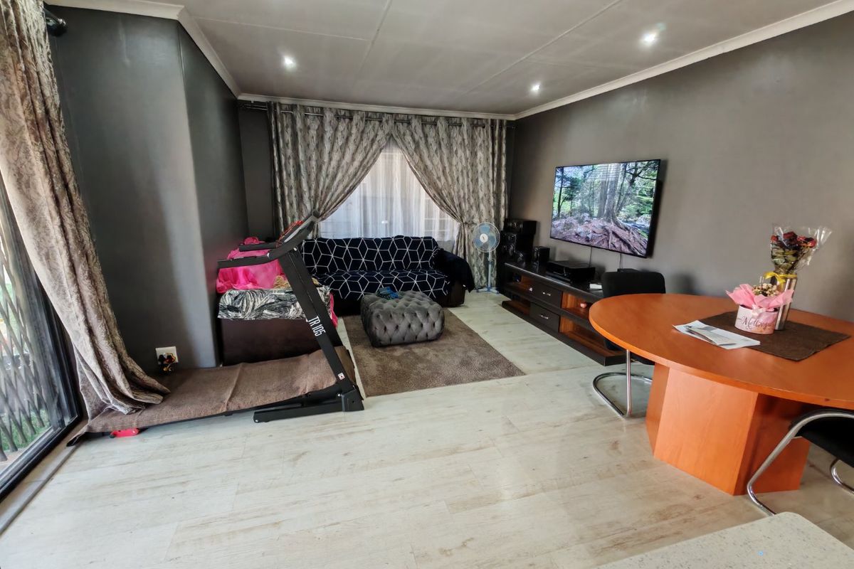 A spacious living area featuring modern laminate flooring, recessed downlighting, and a large sliding glass door providing natural light.