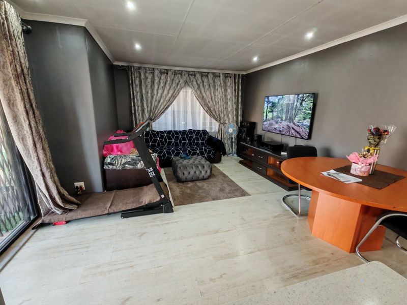 A spacious living area featuring modern laminate flooring, recessed downlighting, and a large sliding glass door providing natural light.