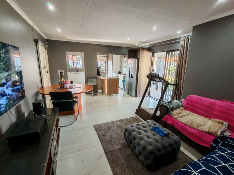 Open-plan living and dining area featuring laminate flooring, recessed lighting, and direct access to an outdoor patio through sliding glass doors.