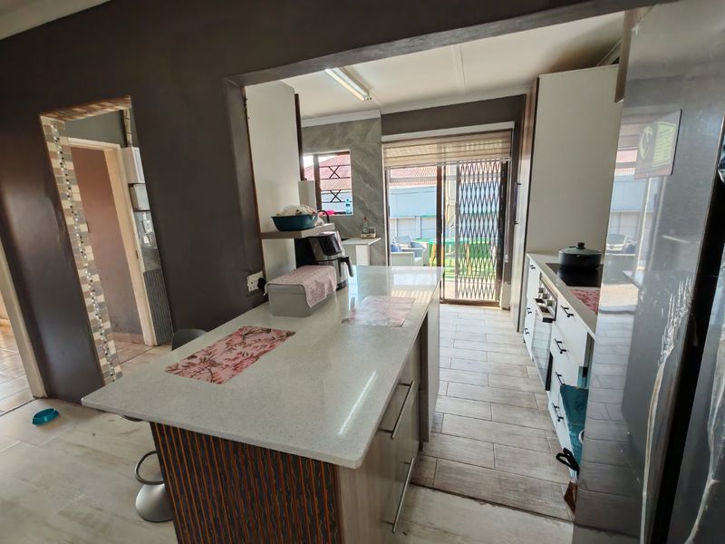 Modern kitchen featuring a central island with stone countertops, built-in cabinetry, integrated oven and hob, and direct access to the outdoor patio area.