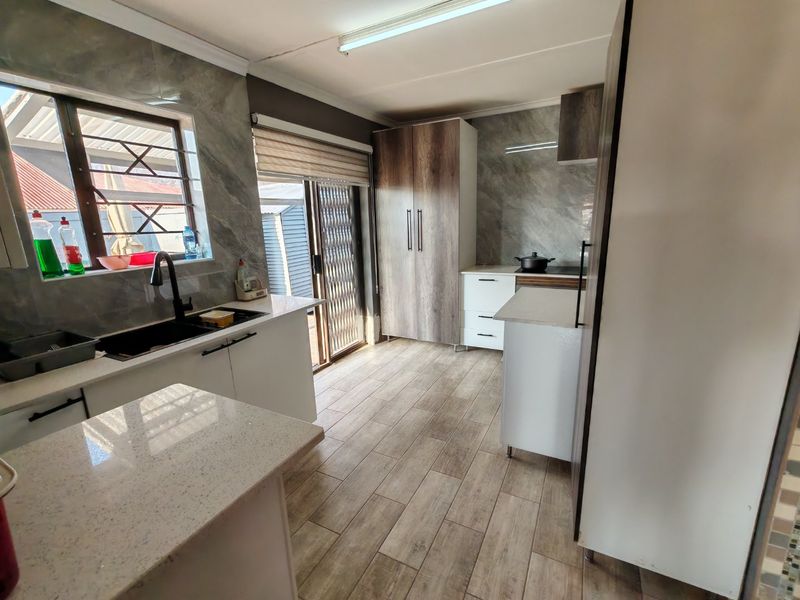 Modern kitchen featuring stone countertops, built-in cabinetry, tiled splashbacks, and a sleek undermount sink with a contemporary mixer tap.