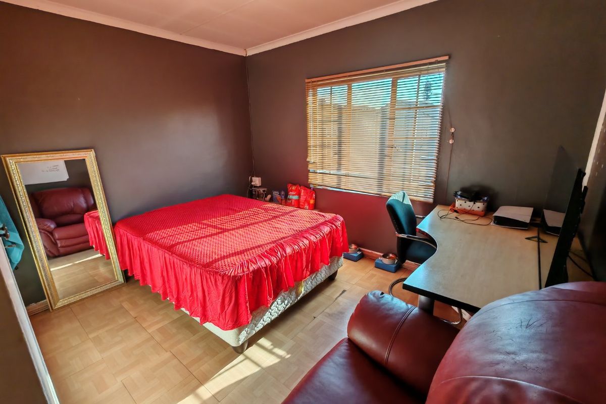 A bedroom featuring tiled flooring, dark painted walls, and venetian blinds, providing a functional space with natural light.