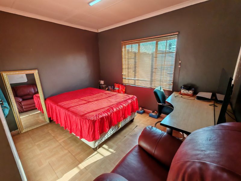 A bedroom featuring tiled flooring, dark painted walls, and venetian blinds, providing a functional space with natural light.