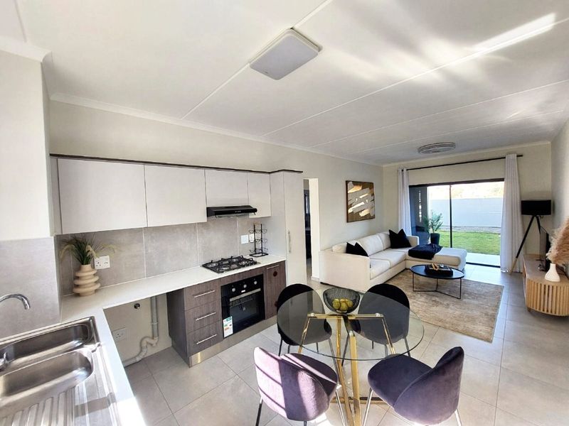 Modern open-plan living area featuring a contemporary kitchen with built-in appliances, tiled flooring, and seamless access to the outdoor patio through sliding doors.