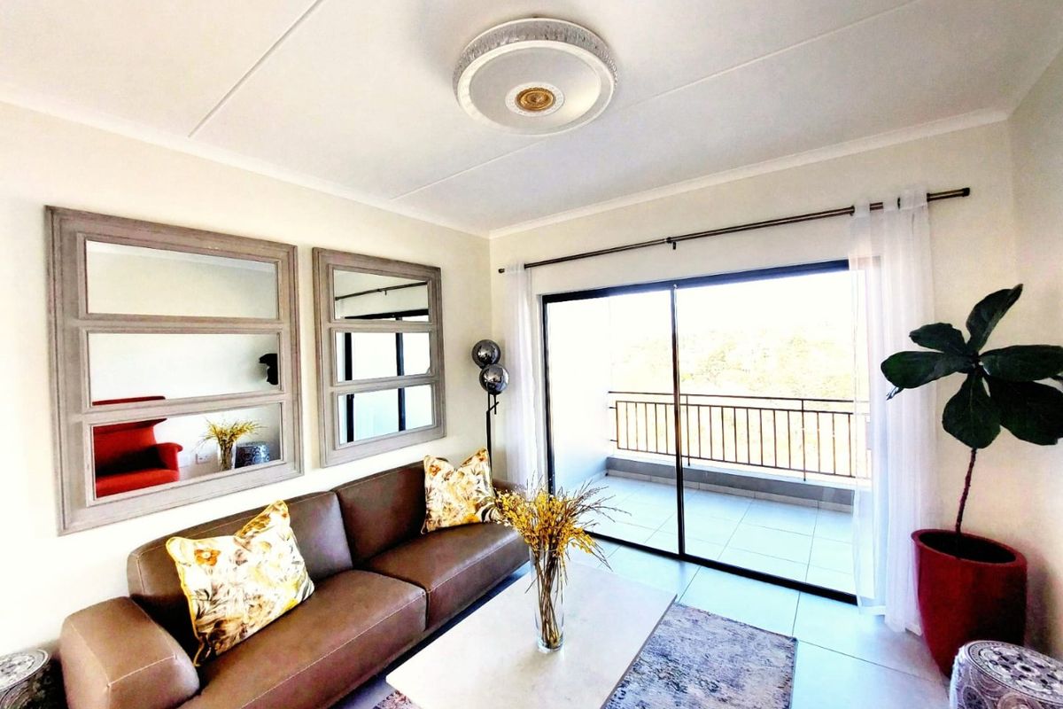 A bright living room featuring tiled flooring and a large sliding glass door that provides access to an outdoor balcony area.