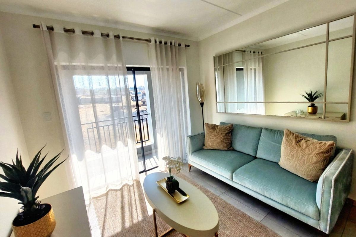 A bright and well-maintained living room featuring tiled flooring and a sliding glass door that opens onto a balcony.