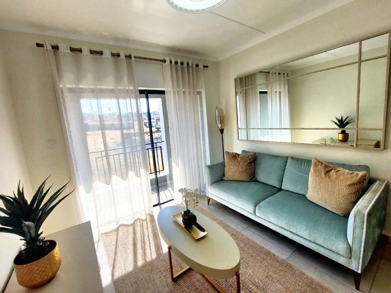 A bright and well-maintained living room featuring tiled flooring and a sliding glass door that opens onto a balcony.