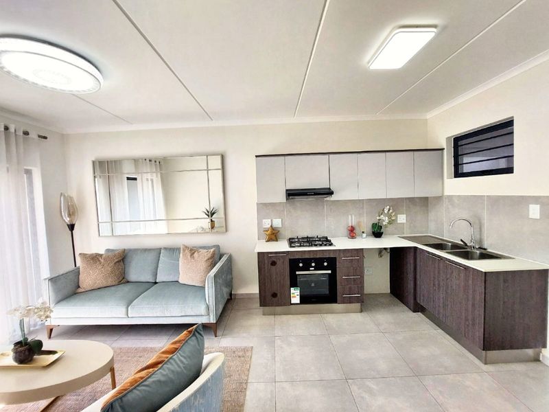 Modern open-plan living area featuring a contemporary kitchen with built-in cabinetry, gas hob, oven, and tiled flooring throughout.