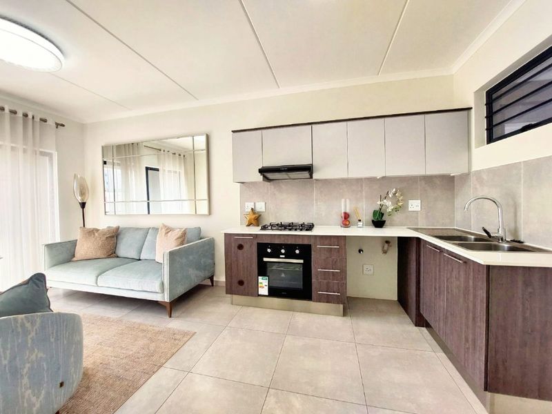 Modern open-plan living area featuring a well-appointed kitchen with built-in cabinetry, gas hob, oven, and sleek tiled finishes throughout.
