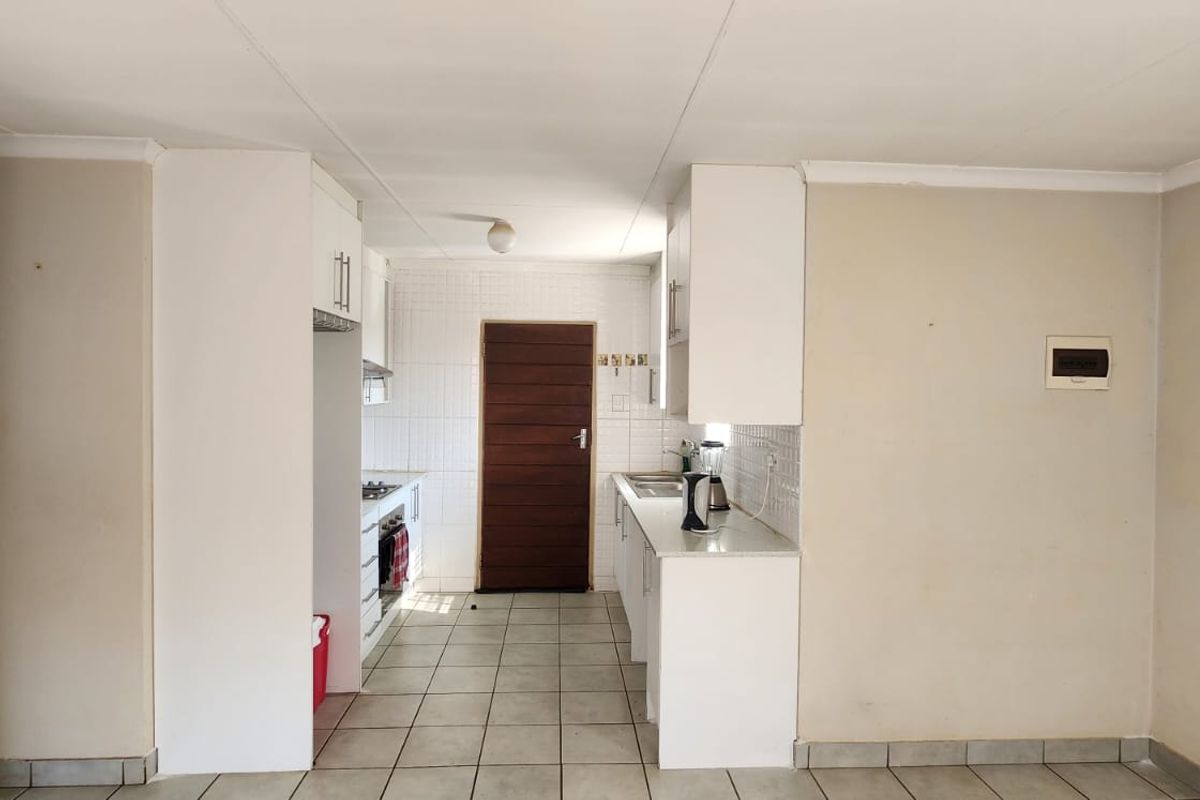 A functional kitchen featuring white built-in cabinetry, tiled flooring, and a tiled backsplash, offering a clean and practical layout for culinary activities.