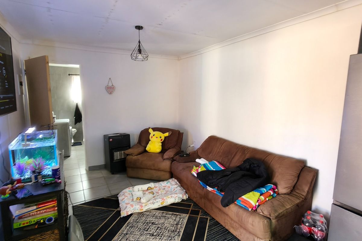 A living room area featuring tiled flooring and a pendant light fixture, with a view leading into an adjacent bathroom space.