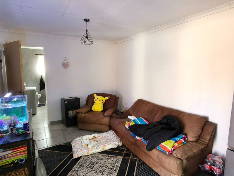 A living room area featuring tiled flooring and a pendant light fixture, with a view leading into an adjacent bathroom space.
