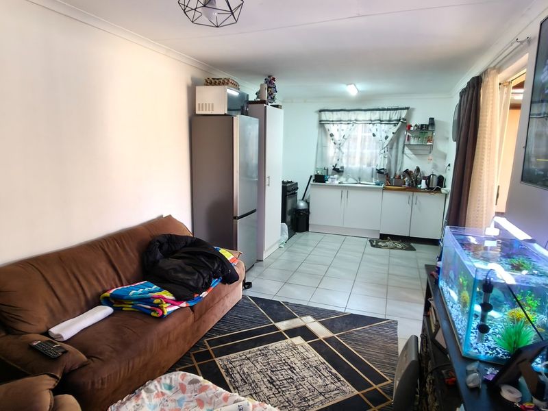 Open plan living area featuring tiled flooring and a functional kitchen space with built-in cabinetry and sink.