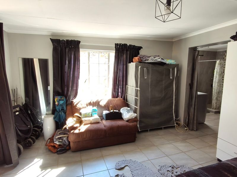 A bedroom featuring tiled flooring, a sliding door leading to an outdoor area, and a built-in wardrobe with an en-suite bathroom access.