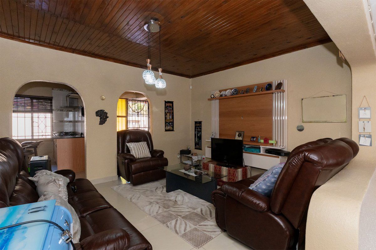 A comfortable living room featuring a distinctive timber-clad ceiling, arched doorways leading to adjacent spaces, and a built-in media wall unit.