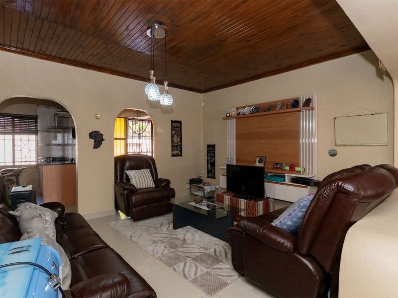 A comfortable living room featuring a distinctive timber-clad ceiling, arched doorways leading to adjacent spaces, and a built-in media wall unit.