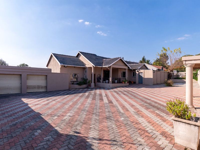 Front view of a residential property featuring a spacious paved driveway, double garage, and a covered entrance porch under a tiled roof.