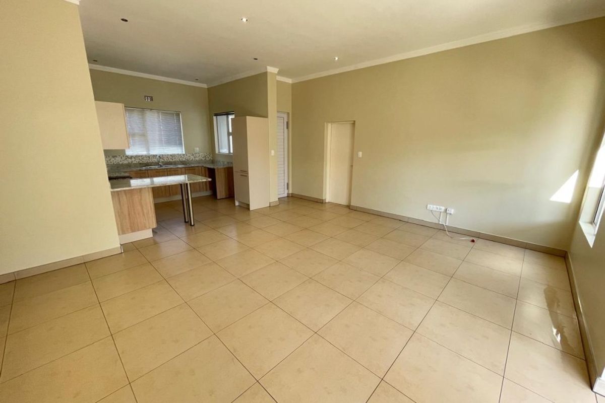 Spacious open-plan living area featuring tiled flooring, recessed lighting, and a functional kitchen with granite countertops and ample cabinetry.