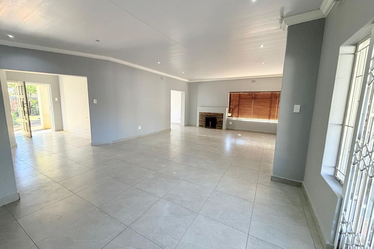 Spacious, open-plan living area featuring neutral tiled flooring, recessed lighting, and a built-in fireplace, offering a bright and versatile space.