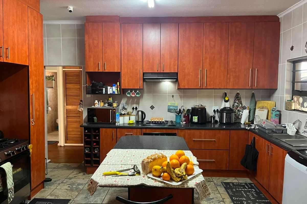 A functional kitchen featuring wood-finish cabinetry, dark countertops, integrated appliances, and tiled flooring, offering ample storage and workspace.