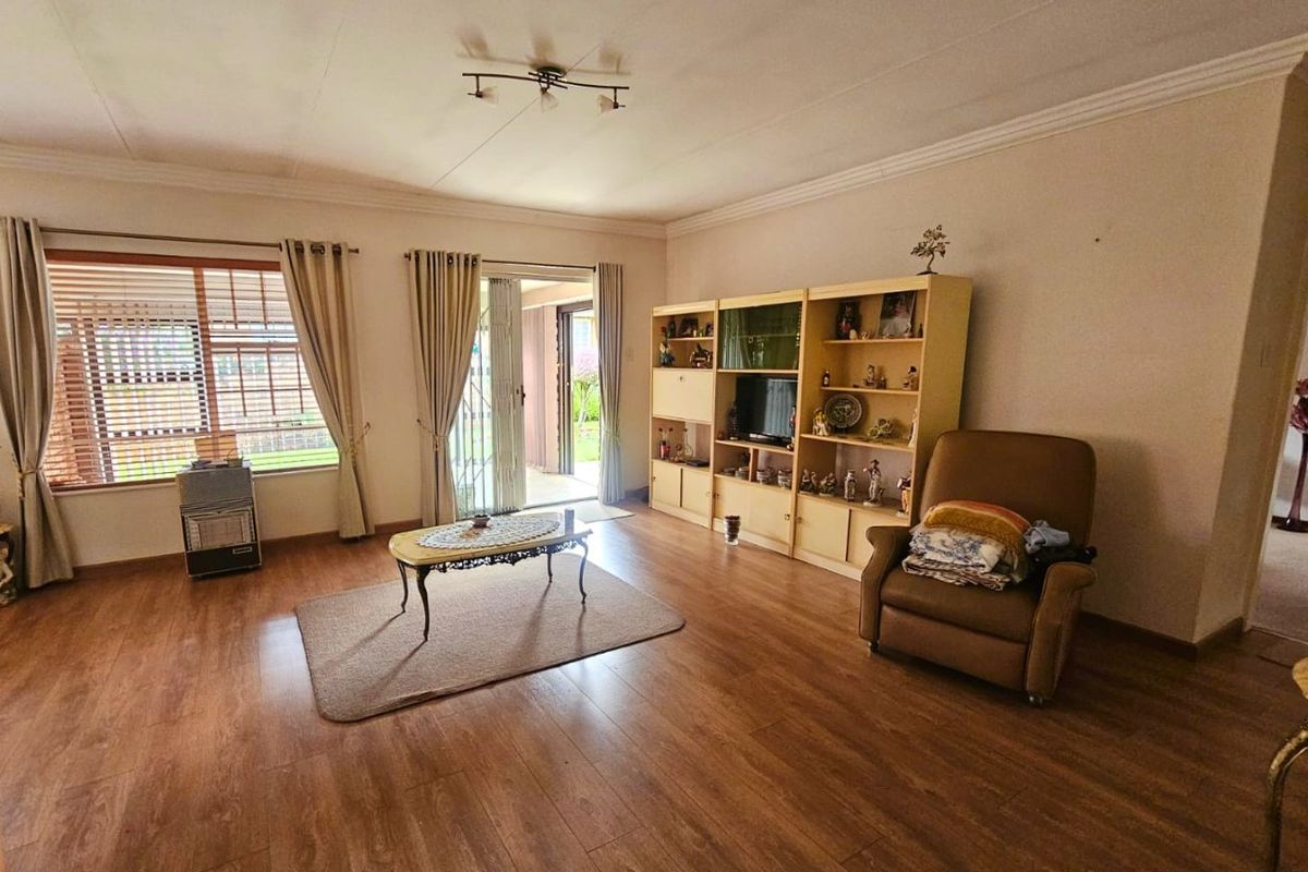 Spacious living room featuring laminate flooring, large windows, and a sliding glass door providing access to the outdoor area.