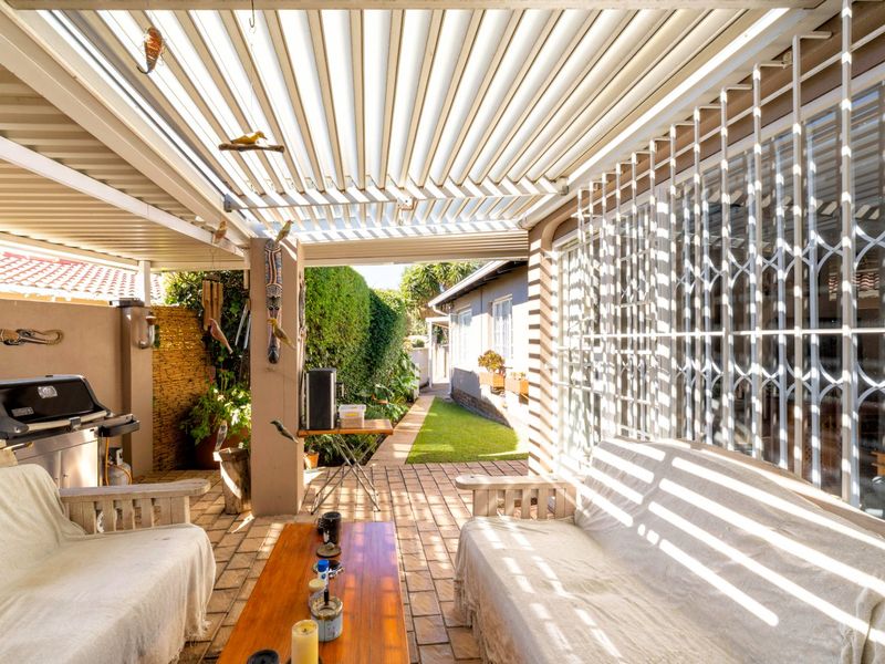 A covered outdoor patio featuring a louvre roof system, paved flooring, and direct access to the home through a secure sliding door.