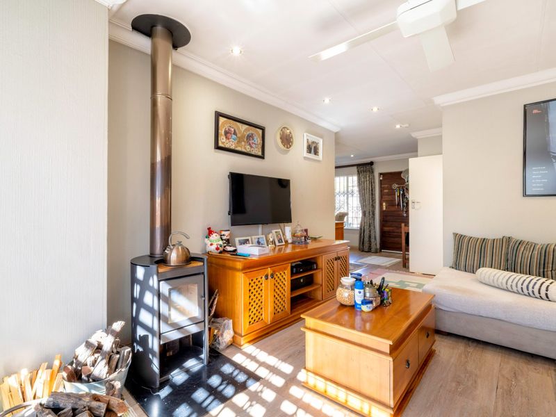 A cozy living room featuring a modern freestanding fireplace, laminate flooring, and recessed lighting, creating a warm and inviting atmosphere.