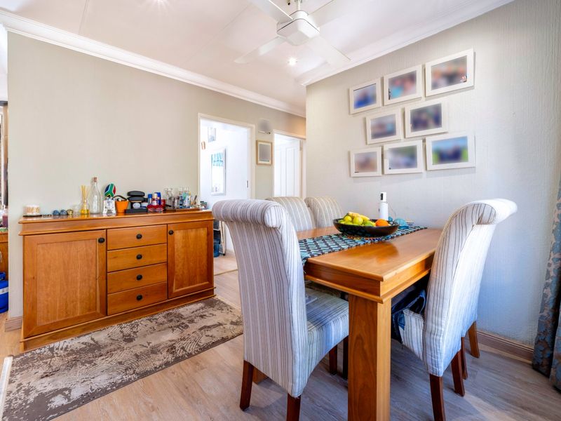 A well-maintained dining area featuring laminate flooring, coving, and a ceiling fan, providing a comfortable space for meals.