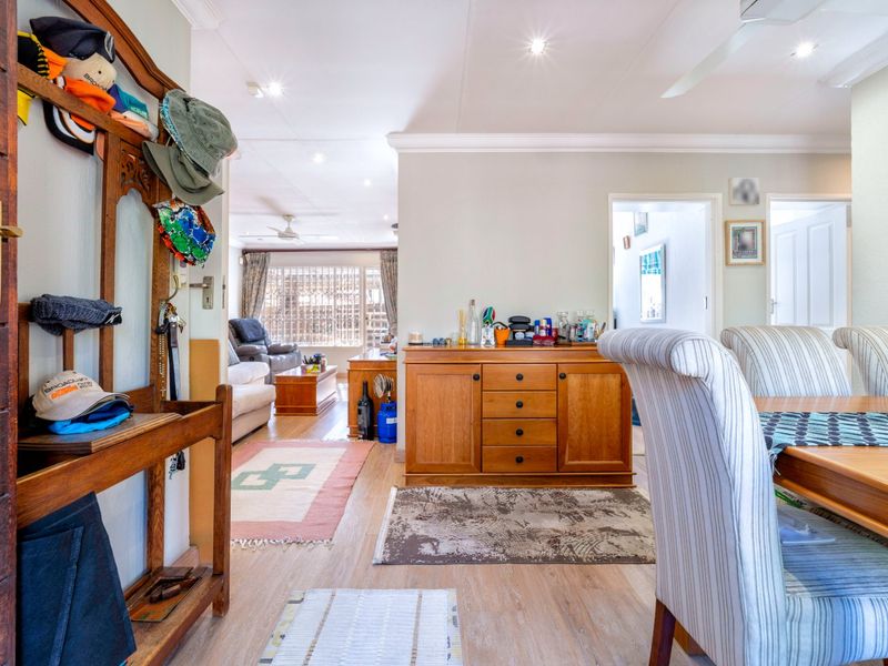 Open plan living and dining area featuring laminate flooring, recessed downlighting, and ceiling fans, creating a functional and connected living space.