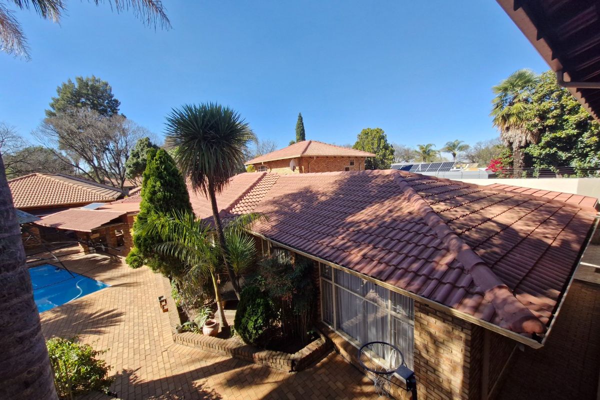 Aerial view of the property showing the tiled roof, brick paved courtyard, and swimming pool area.