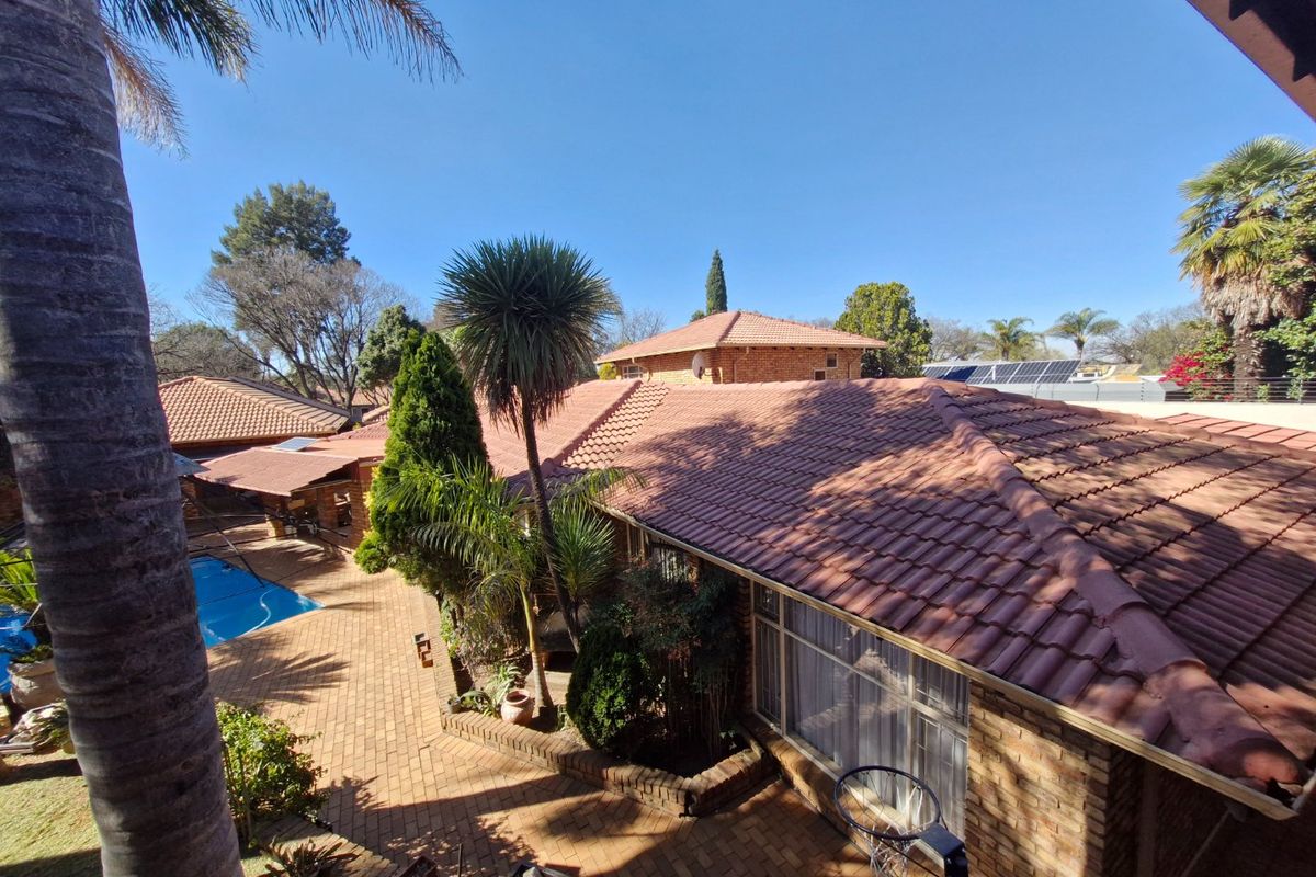 Elevated view of the rear property featuring a swimming pool, brick paved courtyard, and terracotta tiled roof with integrated solar panels.