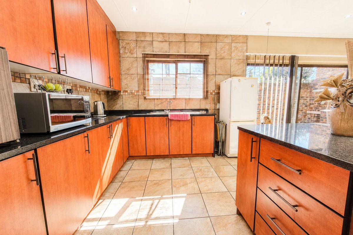 A functional kitchen featuring warm-toned cabinetry, granite countertops, tiled backsplash, and a central island, offering ample storage and workspace.