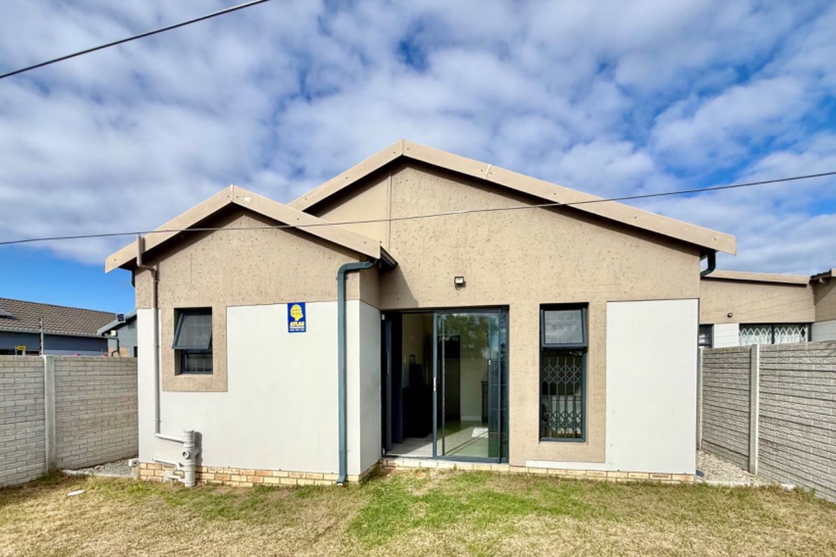 Rear view of the house featuring a sliding glass door, security gate, and enclosed yard with precast concrete boundary walls.