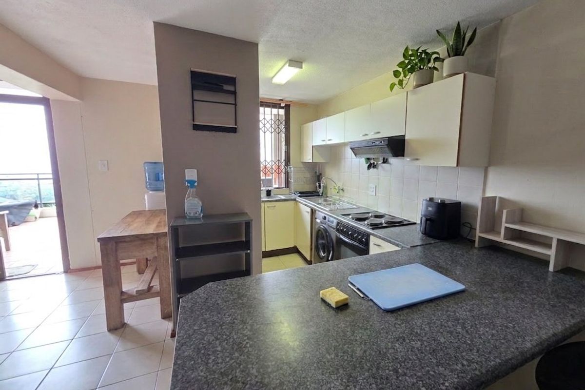 Functional kitchen featuring laminate countertops, built-in cabinetry, and integrated appliances, with direct access to an adjacent balcony area.