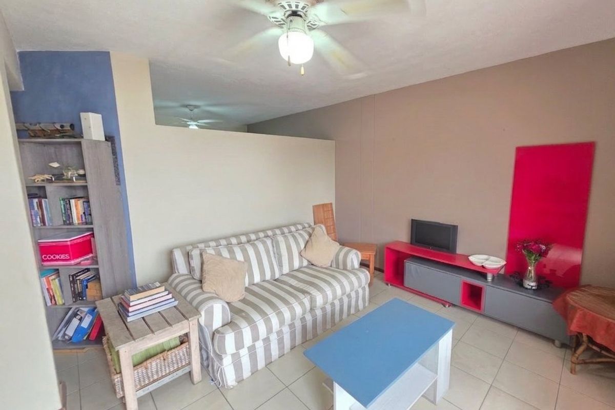 A living room area featuring tiled flooring and a ceiling fan, providing a functional space for relaxation.