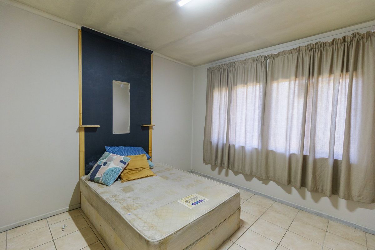 A bedroom featuring tiled flooring and a built-in headboard feature, offering a functional space ready for cosmetic updates and modernization.