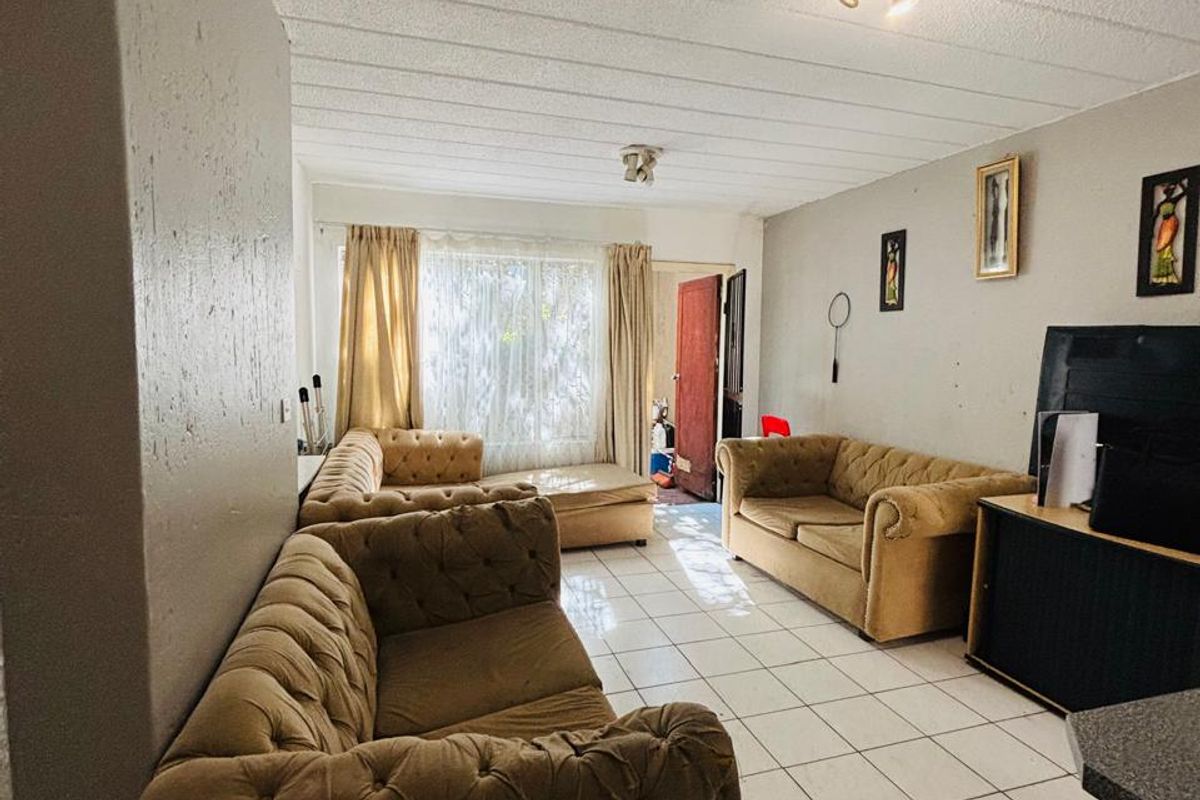 A living room featuring tiled flooring and a textured ceiling, offering a functional space with potential for cosmetic updates to enhance its appeal.
