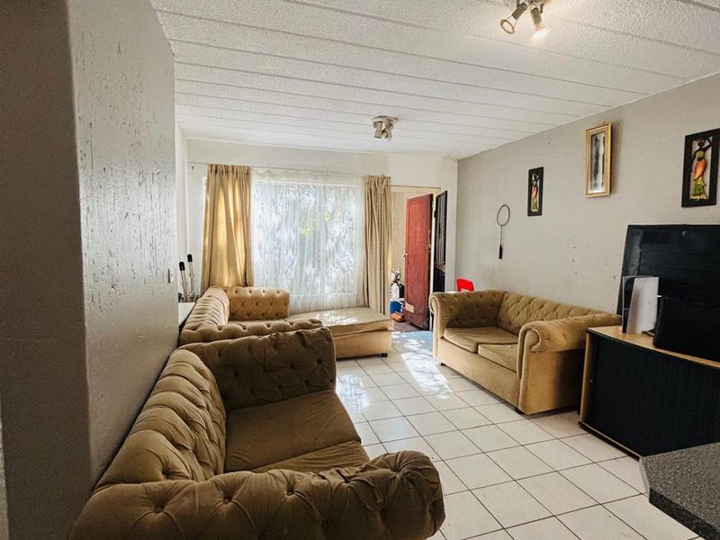 A living room featuring tiled flooring and a textured ceiling, offering a functional space with potential for cosmetic updates to enhance its appeal.