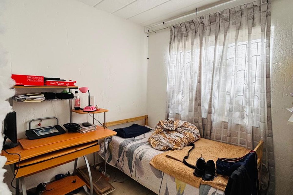 A compact bedroom featuring tiled flooring and a window with a curtain track, requiring cosmetic updates to improve the overall finish.