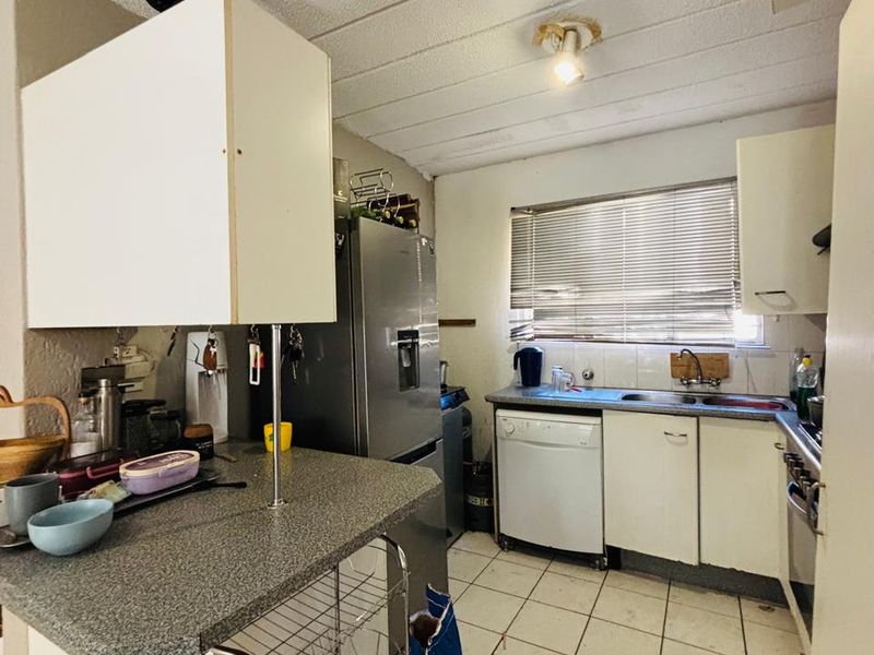 A functional kitchen featuring laminate countertops, built-in cabinetry, and tiled flooring, offering potential for modernization and cosmetic updates.