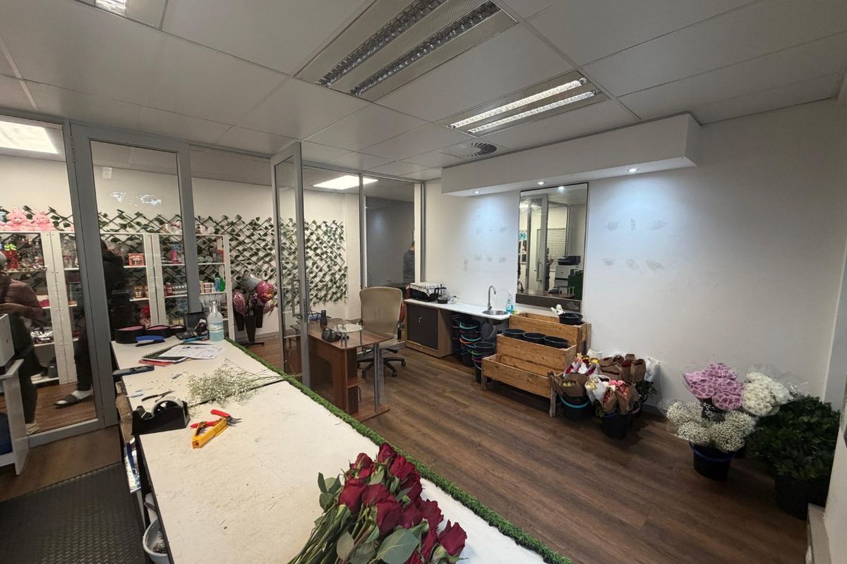 Commercial office space featuring glass partitions, suspended ceilings, laminate flooring, and a built-in sink area, suitable for retail or professional use.