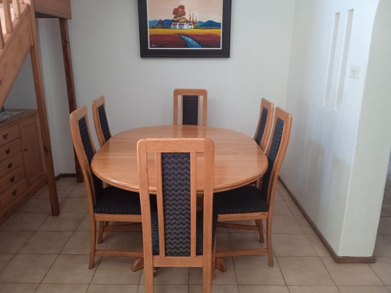 A dining area featuring tiled flooring and an adjacent wooden staircase, providing a functional space for meals.
