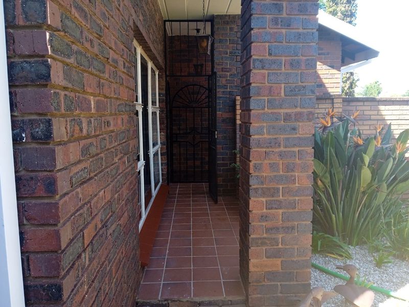 A covered front entrance featuring face brick construction, tiled flooring, and a secure metal gate.